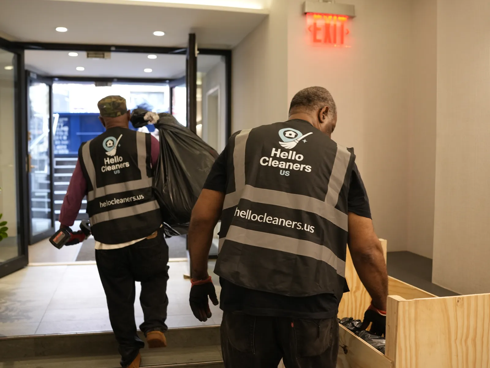 Hello Cleaners crew carrying bags out of a building
