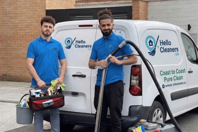 Two Hello Cleaners team members with supplies beside company vehicles