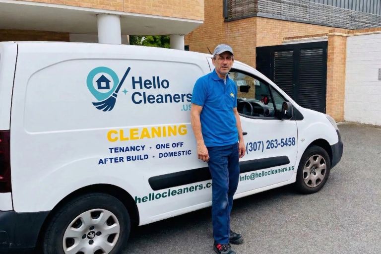 Hello Cleaners cleaner standing beside a branded service van showing the hellocleaners.us contact details