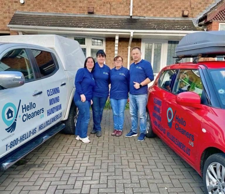 Four Hello Cleaners crew members in branded polo shirts standing between two Hello Cleaners vehicles